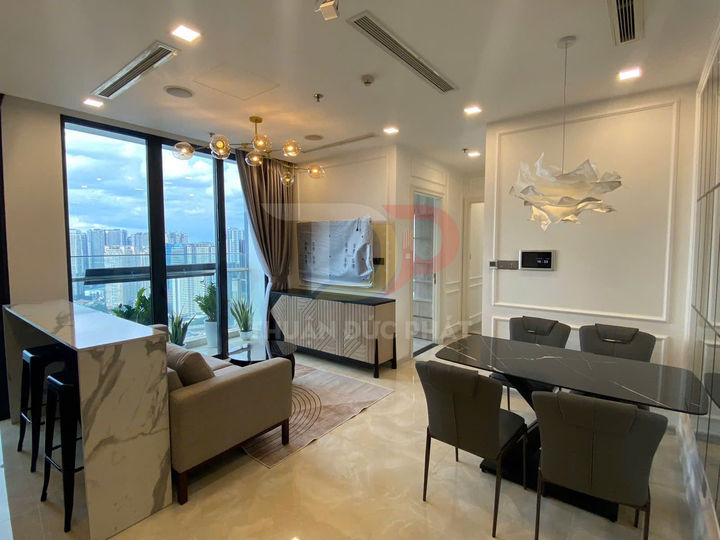 Phòng khách và bếp căn hộ chung cư hiện đại với bàn ăn đá, sofa nhỏ và cửa kính lớn nhìn ra ban công thành phố