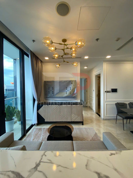 Phòng khách căn hộ cao cấp với sofa xám, bàn trà tròn, kệ tivi hiện đại và đèn trần nghệ thuật