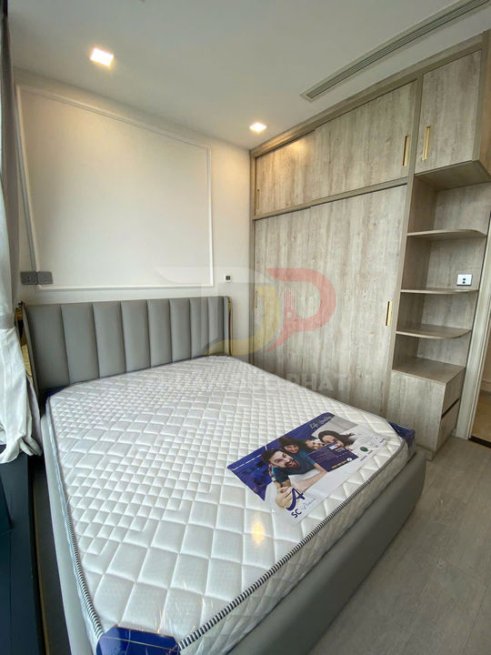 Nệm lò xo trắng trên giường bọc da xám trong phòng ngủ hiện đại có tủ quần áo gỗ cửa lùa