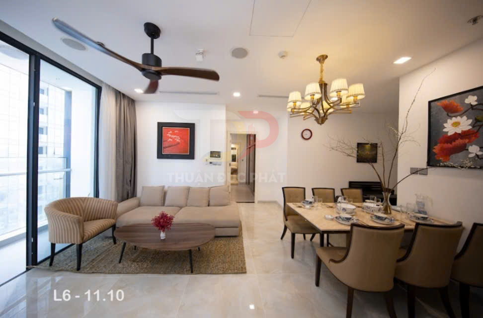 Phòng khách và phòng ăn chung cư hiện đại với sofa be, bàn gỗ tròn và bàn ăn sáu ghế cạnh cửa kính lớn