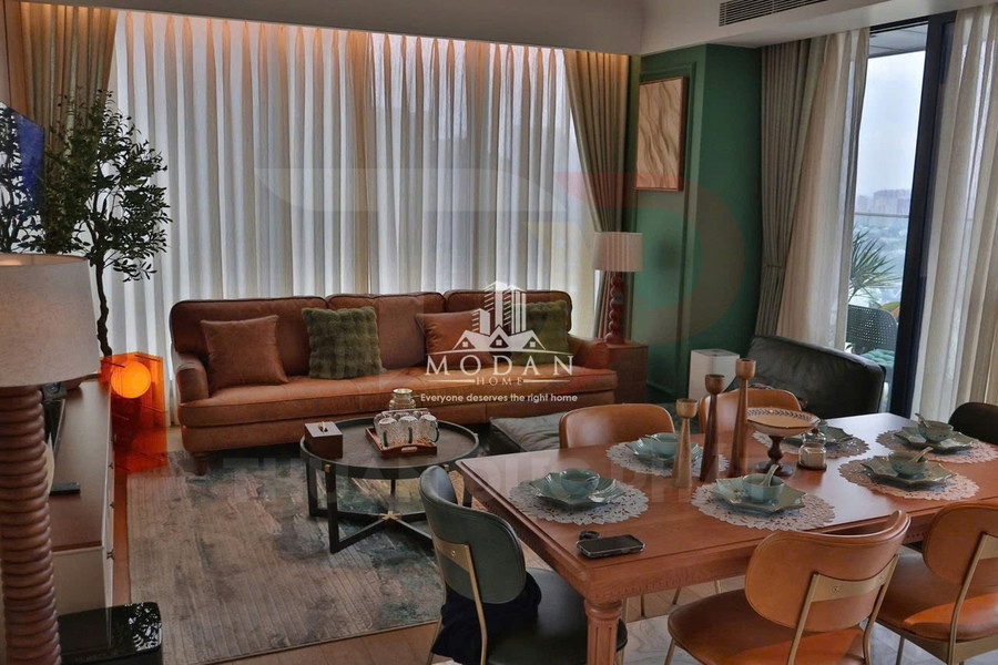 Phòng khách và bàn ăn hiện đại với sofa da nâu, bàn trà, bộ bát đĩa bày biện gọn gàng