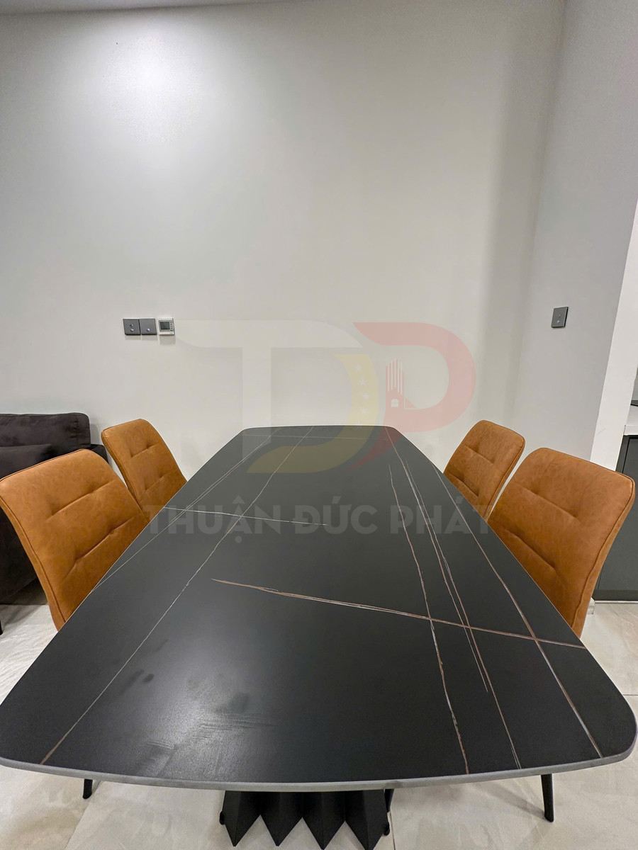 Bàn ăn mặt đá đen hình chữ nhật kèm bốn ghế bọc nệm màu nâu trong phòng hiện đại