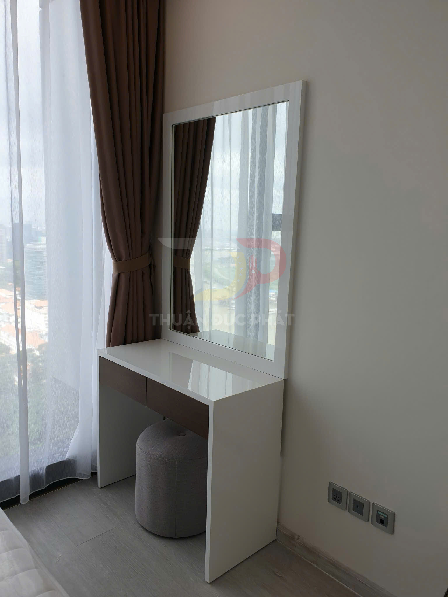 Bàn trang điểm hiện đại màu trắng có gương lớn và ghế đôn tròn trong phòng ngủ cạnh cửa sổ