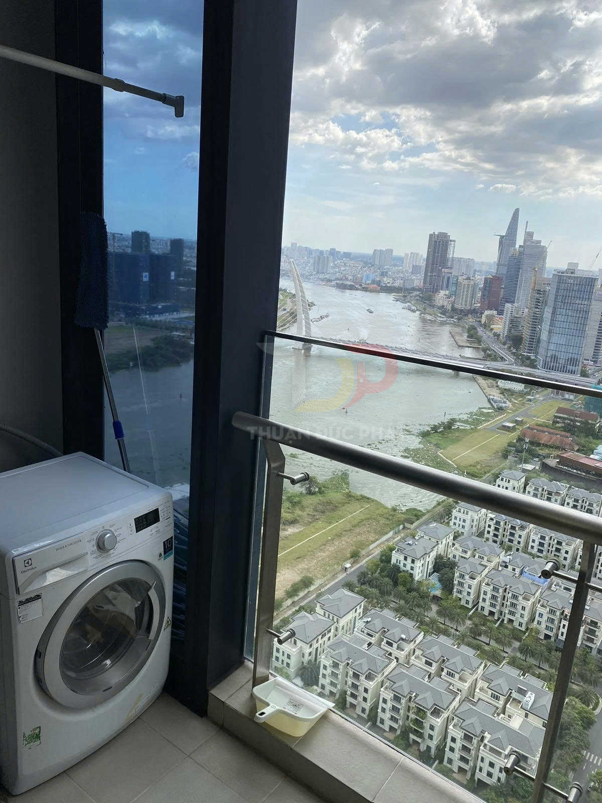 Máy giặt cửa trước Electrolux đặt cạnh cửa sổ ban công căn hộ cao tầng nhìn ra sông và khu đô thị