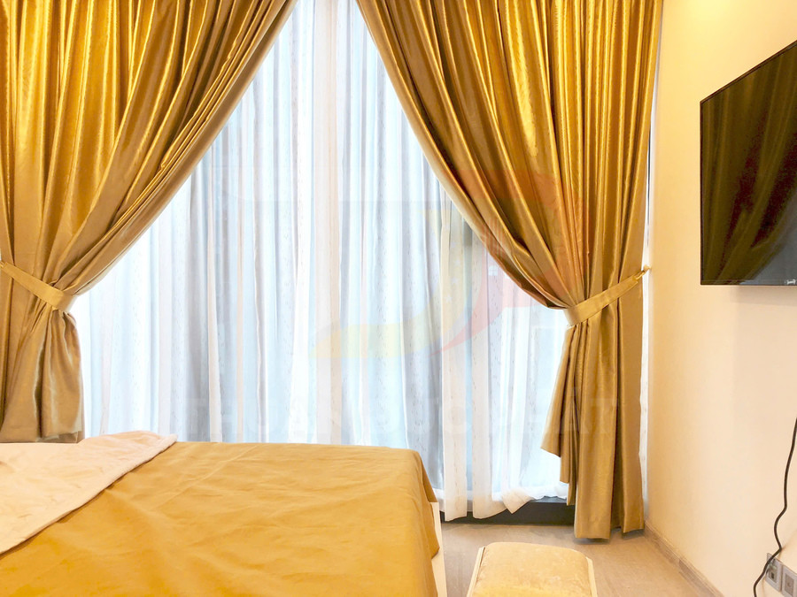 Rèm cửa sổ vải nhung màu vàng đồng trong phòng ngủ hiện đại cạnh giường và tivi treo tường