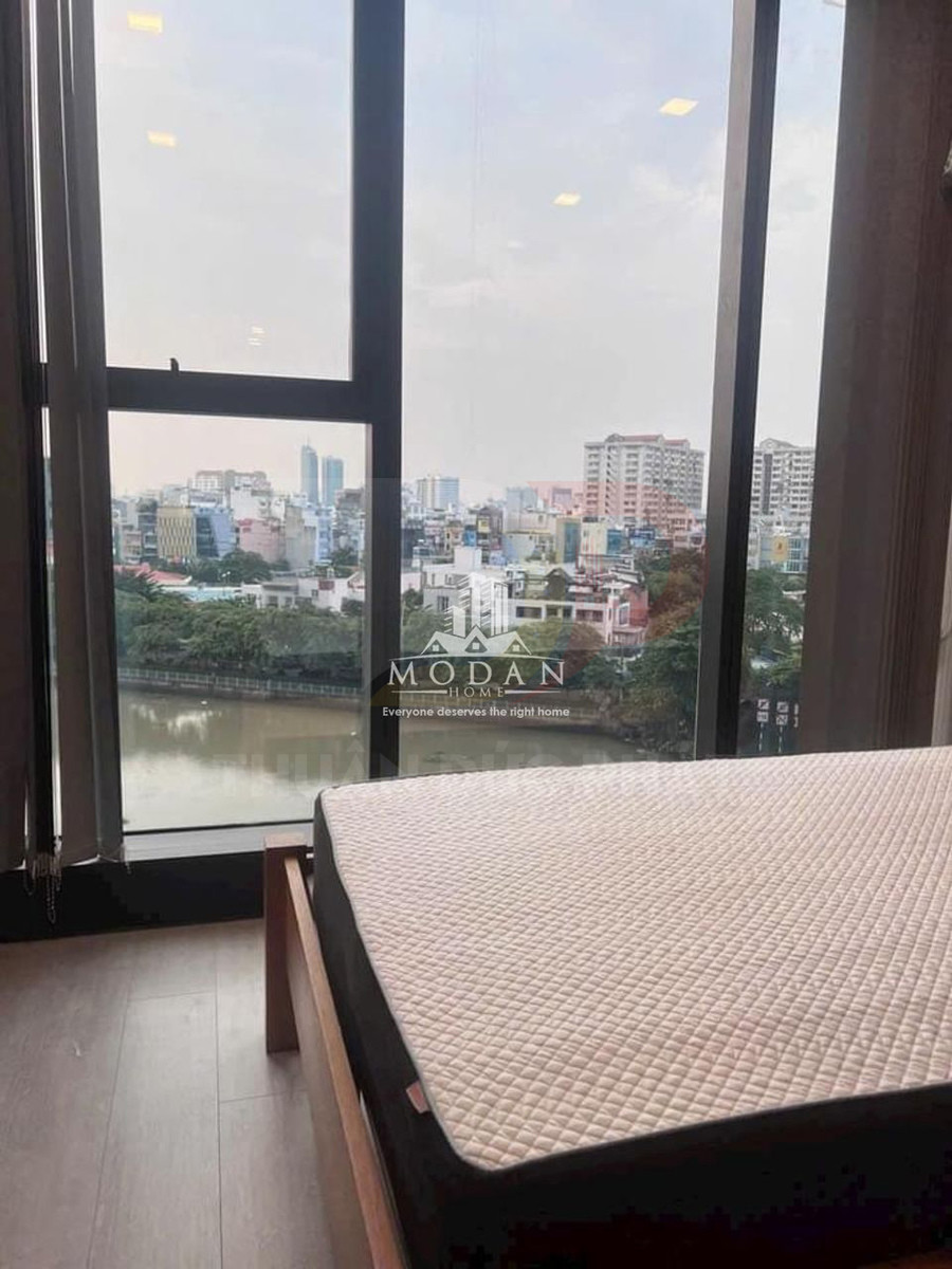 Nệm Modan Home trên giường gỗ cạnh cửa sổ kính lớn nhìn ra sông và thành phố