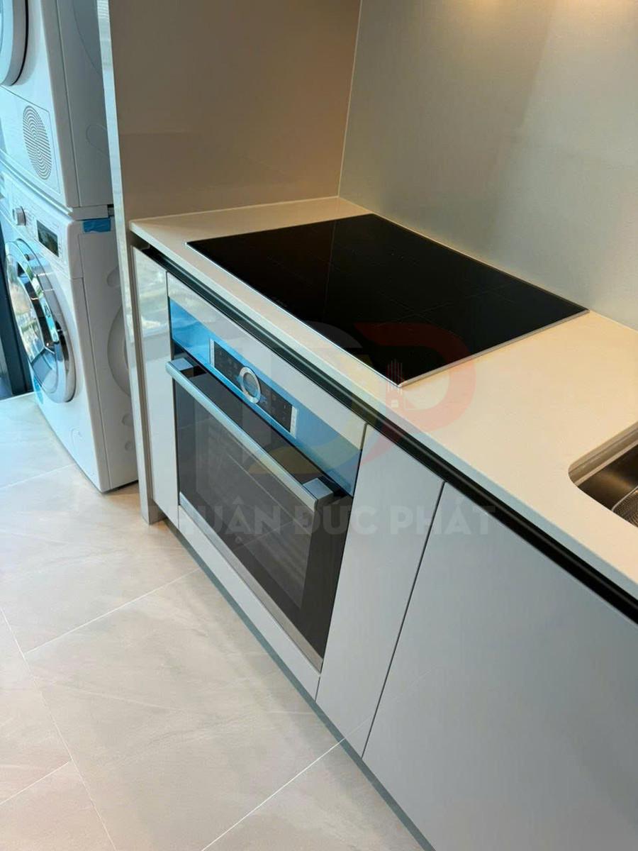 Bếp từ âm và lò nướng âm tủ hiện đại trong căn bếp nhỏ gọn cạnh máy giặt sấy