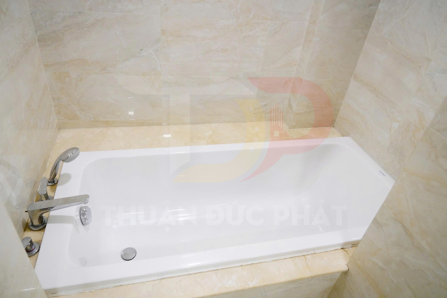 Bồn tắm nằm màu trắng lắp âm tường với vòi nước inox trong phòng tắm ốp đá marble