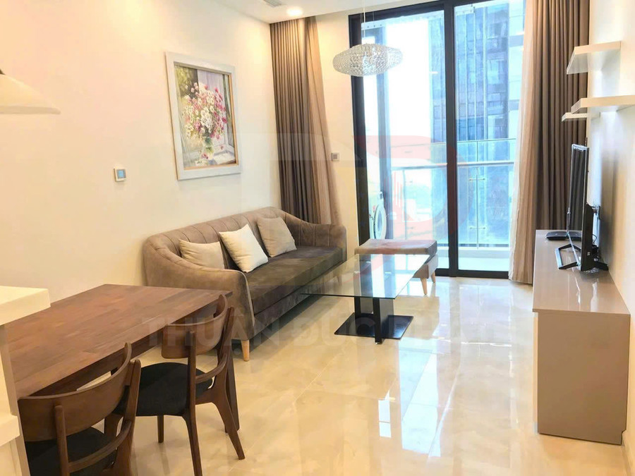 Phòng khách căn hộ hiện đại với sofa nỉ, bàn kính, bàn ăn gỗ và tivi đối diện cửa kính lớn có rèm