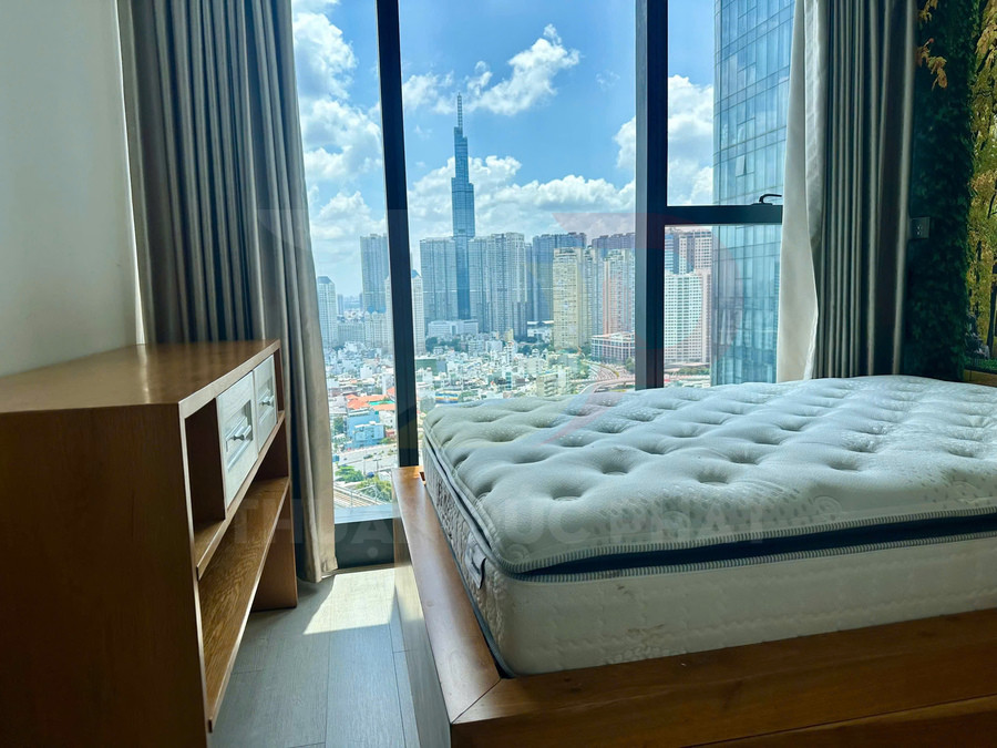 Nệm giường dày đặt trong phòng ngủ cạnh cửa sổ lớn nhìn ra khu chung cư cao tầng