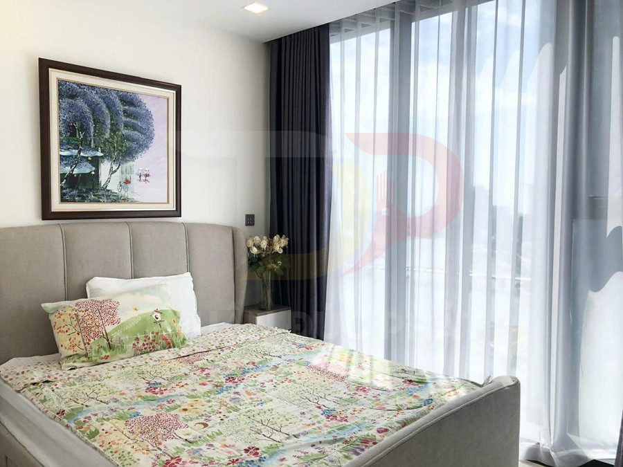 Phòng ngủ sáng với giường bọc nệm, chăn ga họa tiết cây cỏ và cửa sổ kính lớn rèm trắng