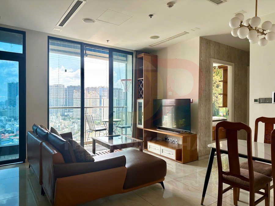 Phòng khách căn hộ hiện đại với sofa da, bàn kính, kệ tivi gỗ và cửa kính lớn nhìn ra thành phố