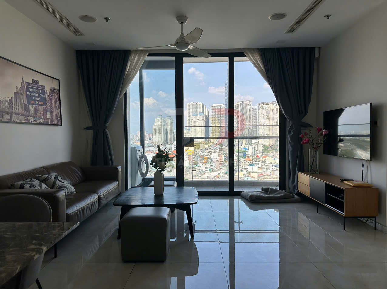 Phòng khách chung cư hiện đại với sofa da, bàn trà gỗ, tivi treo tường và cửa kính lớn nhìn ra thành phố