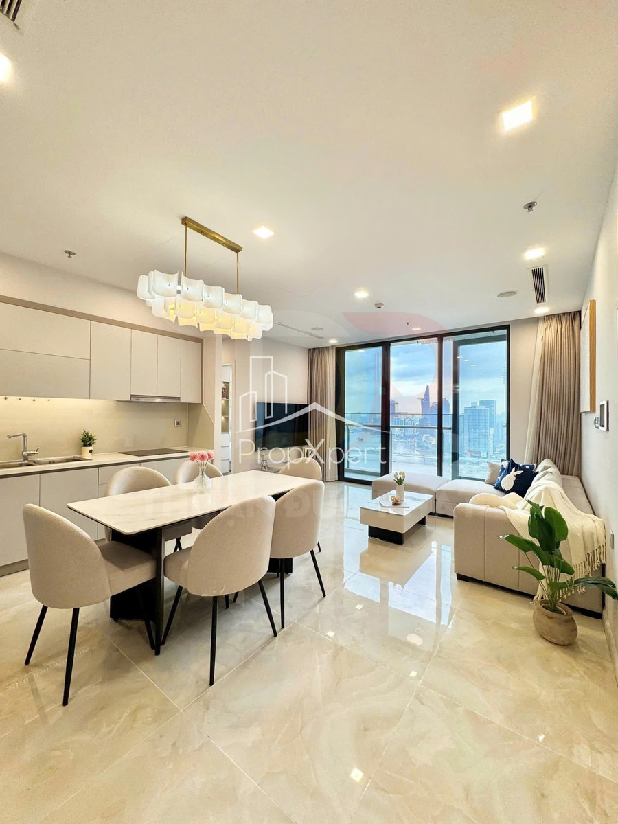 Phòng khách và bếp căn hộ cao cấp với bàn ăn 4 ghế, sofa sáng màu, cửa kính lớn nhìn ra thành phố