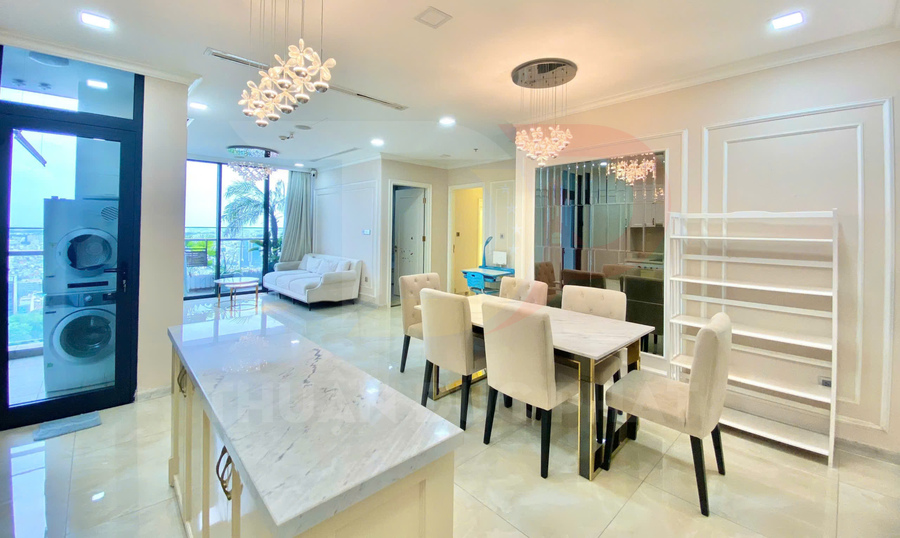 Phòng bếp và phòng ăn chung cư hiện đại với bàn ăn đá, ghế bọc nệm và đảo bếp mặt đá sáng