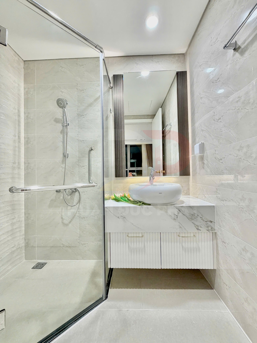 Phòng tắm hiện đại với buồng tắm kính, vòi sen treo tường và lavabo đặt trên tủ đá marble