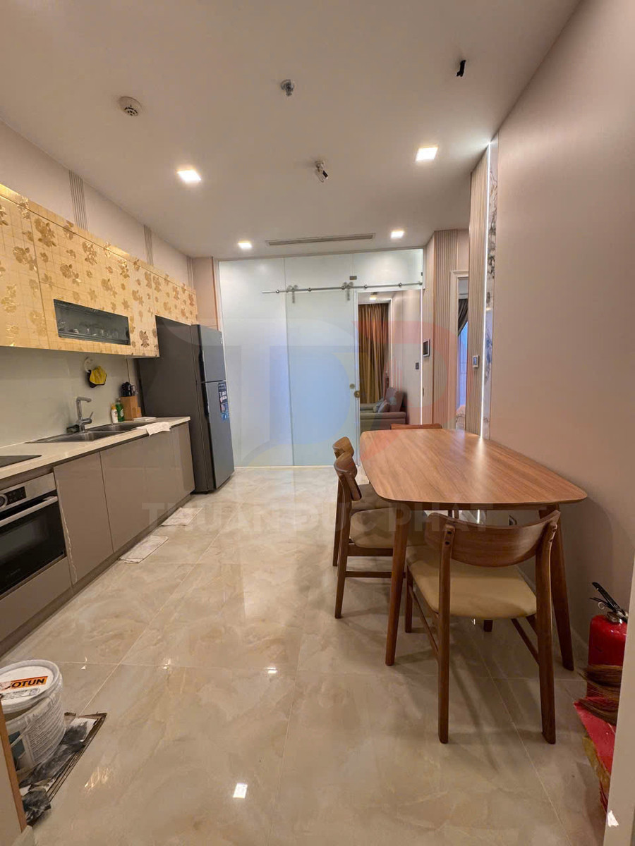 Bàn ăn gỗ bốn ghế trong căn bếp chung cư hiện đại với tủ bếp, lò nướng và tủ lạnh