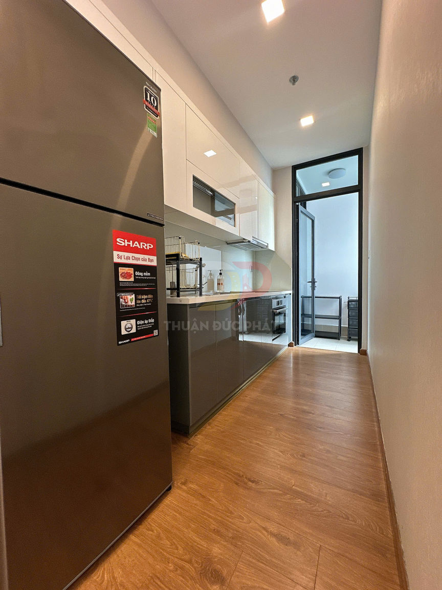 Tủ lạnh Sharp màu xám trong căn bếp nhỏ hiện đại với tủ bếp và sàn gỗ