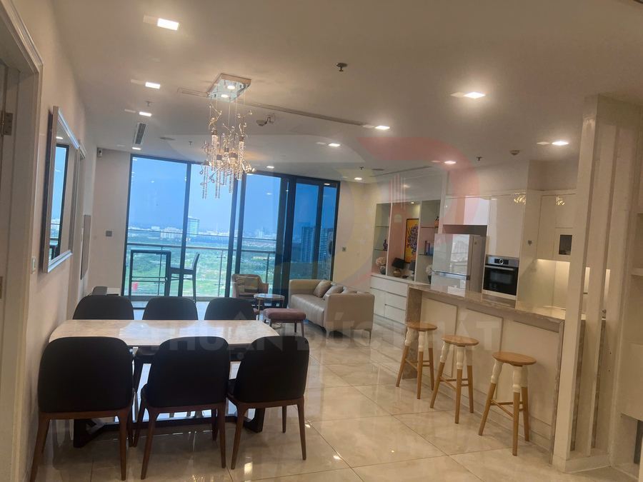 Phòng khách và bếp căn hộ cao cấp với bàn ăn đá, quầy bar ghế gỗ và cửa kính lớn nhìn ra thành phố