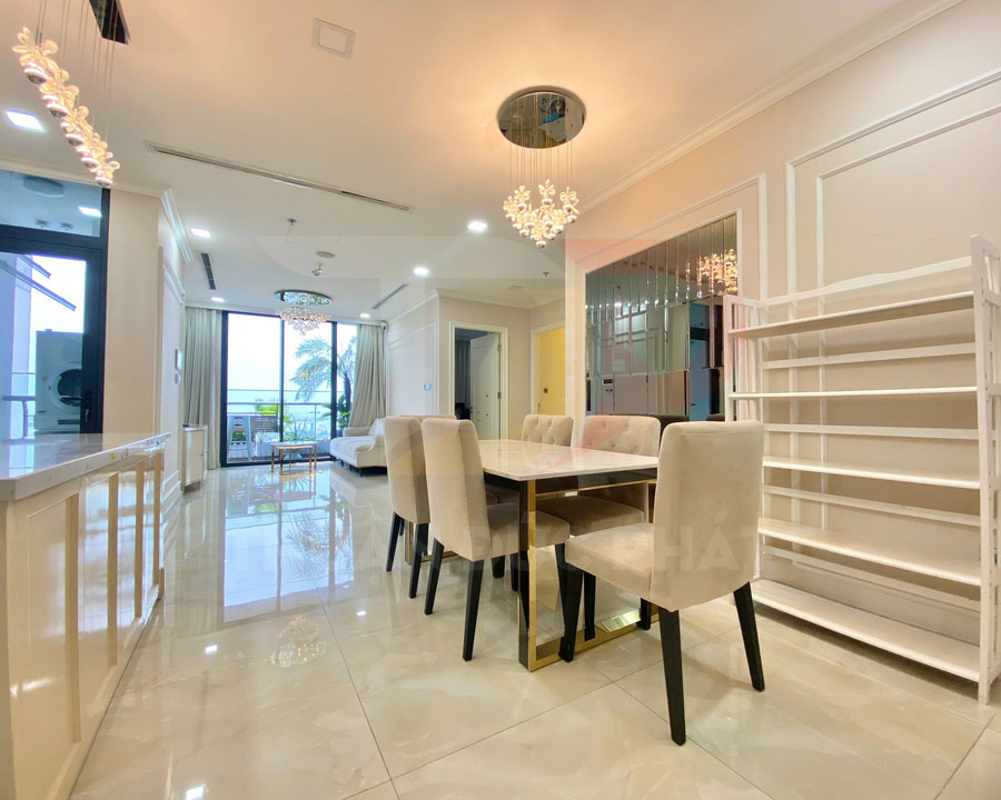 Bộ bàn ăn hiện đại với ghế bọc nệm màu kem trong căn hộ cao cấp sáng rộng có cửa kính nhìn ra ban công