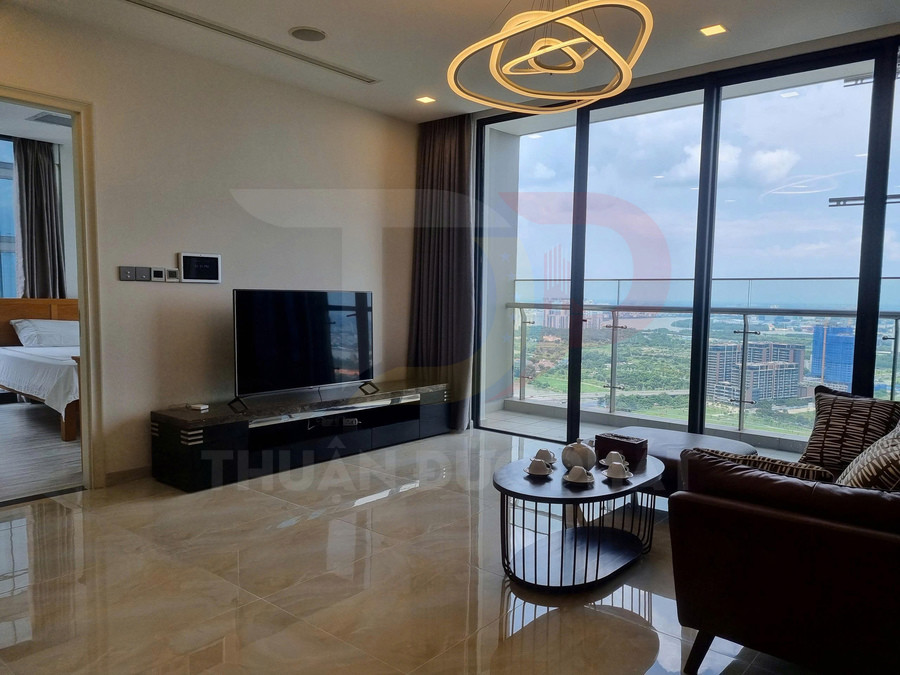 Phòng khách căn hộ cao cấp với sofa da, bàn trà bày bộ ấm chén và tivi lớn cạnh cửa kính view thành phố