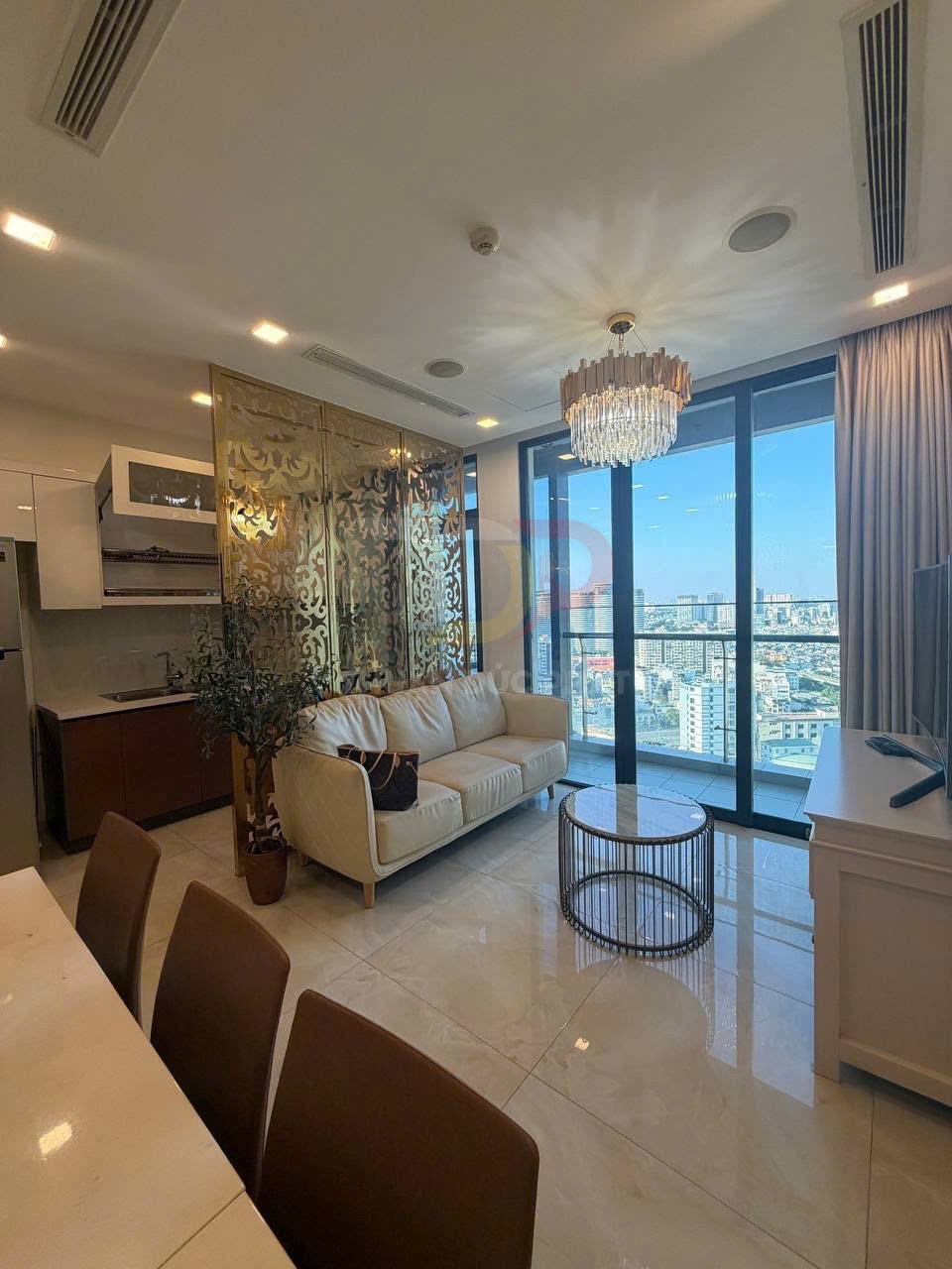 Phòng khách căn hộ cao cấp với sofa kem, bàn trà tròn, bếp liền kề và cửa kính lớn nhìn ra thành phố