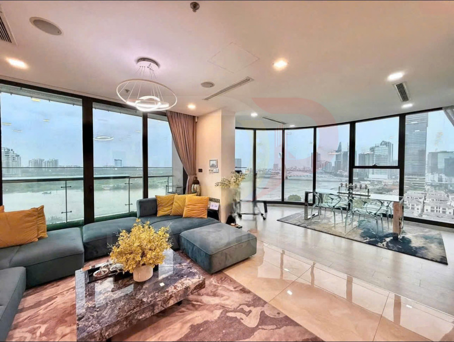 Phòng khách căn hộ cao cấp với sofa chữ L, bàn đá và cửa kính lớn nhìn ra sông và thành phố