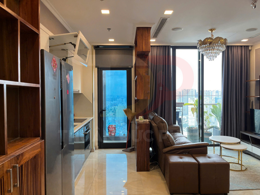 Căn hộ chung cư hiện đại với bếp, tủ lạnh lớn, sofa da nâu và cửa kính nhìn ra ban công thành phố
