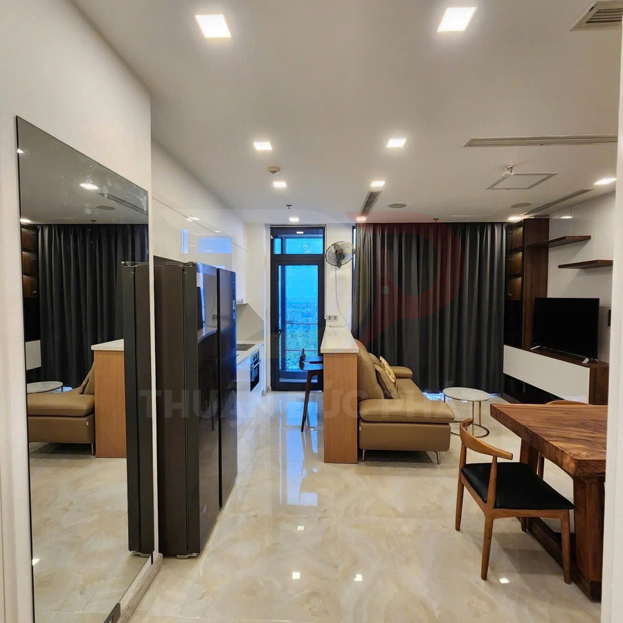 Căn hộ chung cư hiện đại với bếp, tủ lạnh lớn, sofa da, bàn gỗ và tivi phòng khách cạnh cửa kính ban công