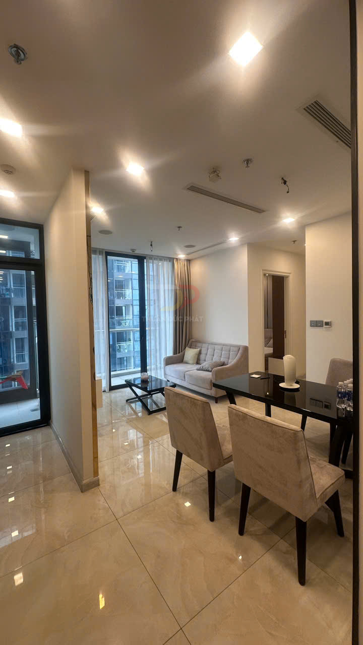 Phòng khách chung cư hiện đại với sofa xám, bàn kính và bàn ăn nhỏ hai ghế cạnh cửa sổ lớn