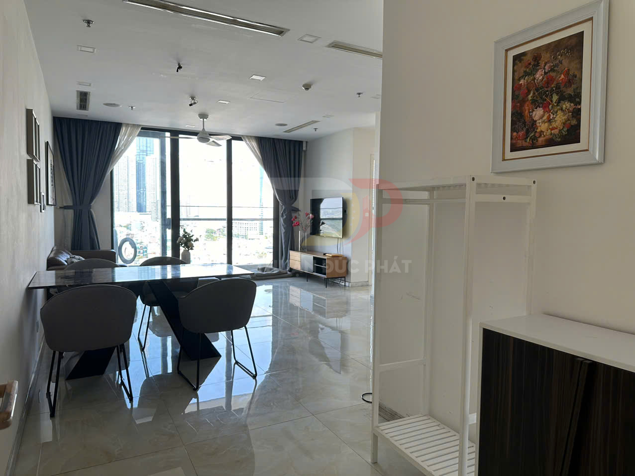 Phòng khách căn hộ hiện đại với bàn ăn, sofa, kệ tivi và cửa kính lớn nhìn ra thành phố