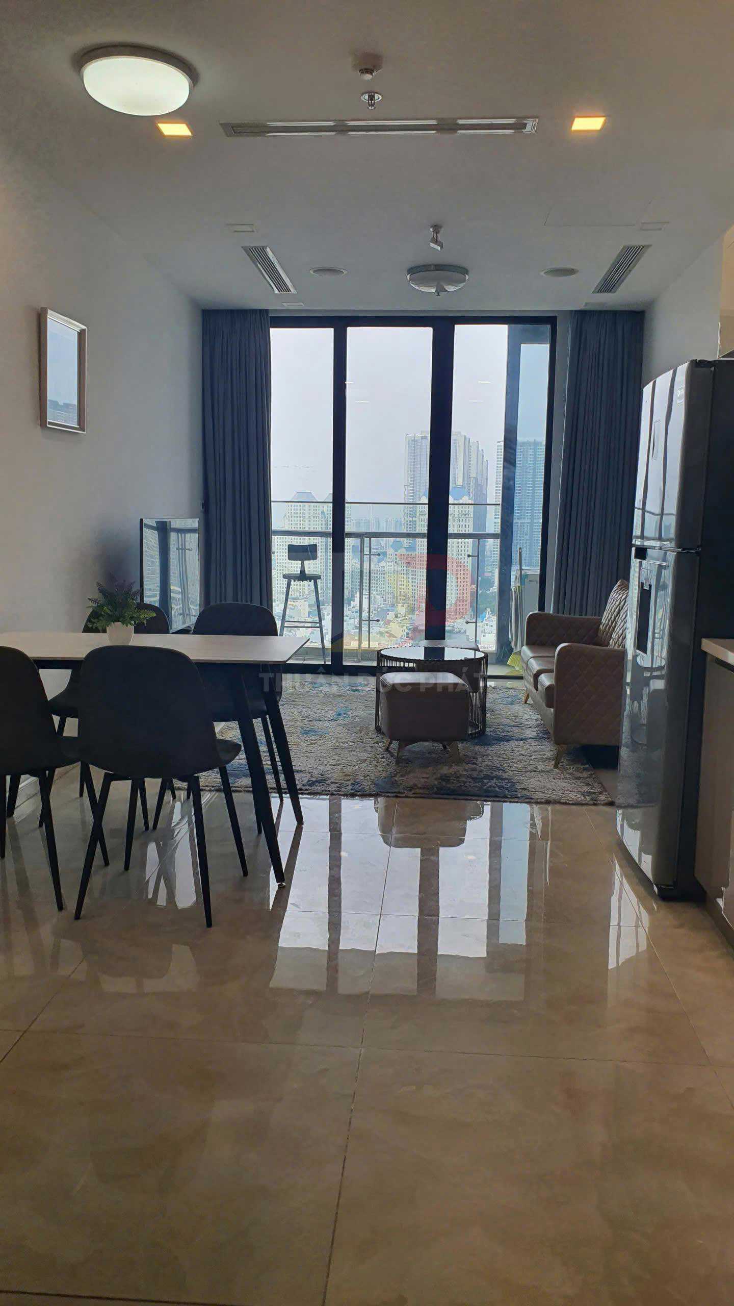 Phòng khách căn hộ hiện đại với bộ bàn ăn, sofa, tủ lạnh và cửa kính lớn nhìn ra thành phố