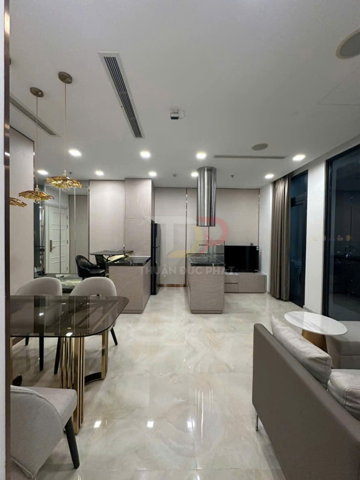 Nội thất phòng khách liền bếp hiện đại với bàn ăn kính, sofa da và sàn gạch bóng cao cấp