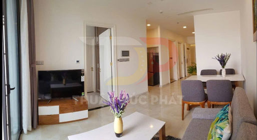 Phòng khách căn hộ hiện đại với sofa xám, bàn trà trắng, tivi màn hình phẳng và bàn ăn gỗ bốn ghế