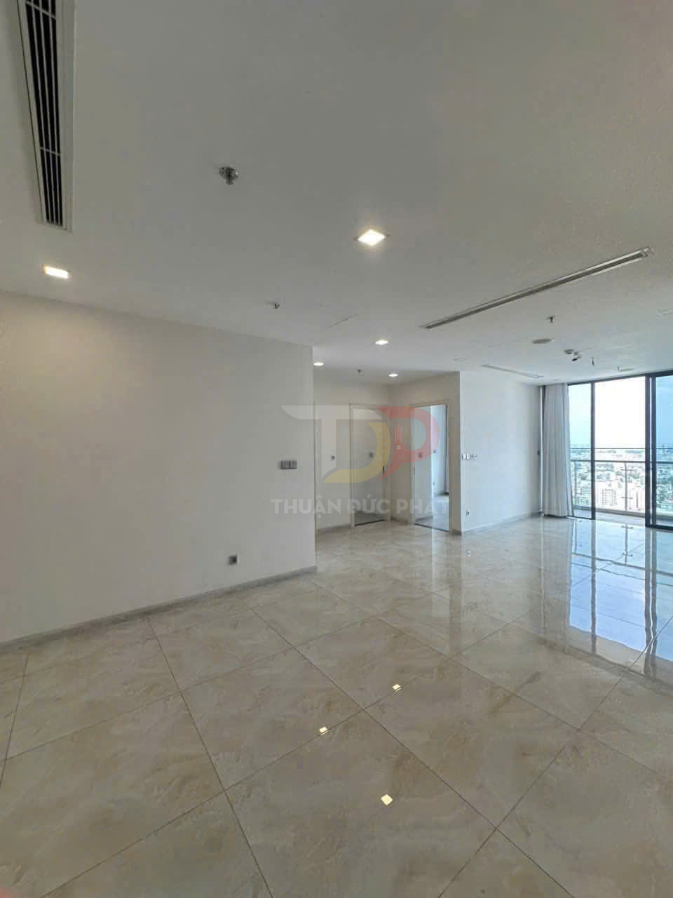 Căn hộ trống lát gạch bóng, trần thạch cao đèn âm trần, cửa kính lớn nhìn ra ban công city view