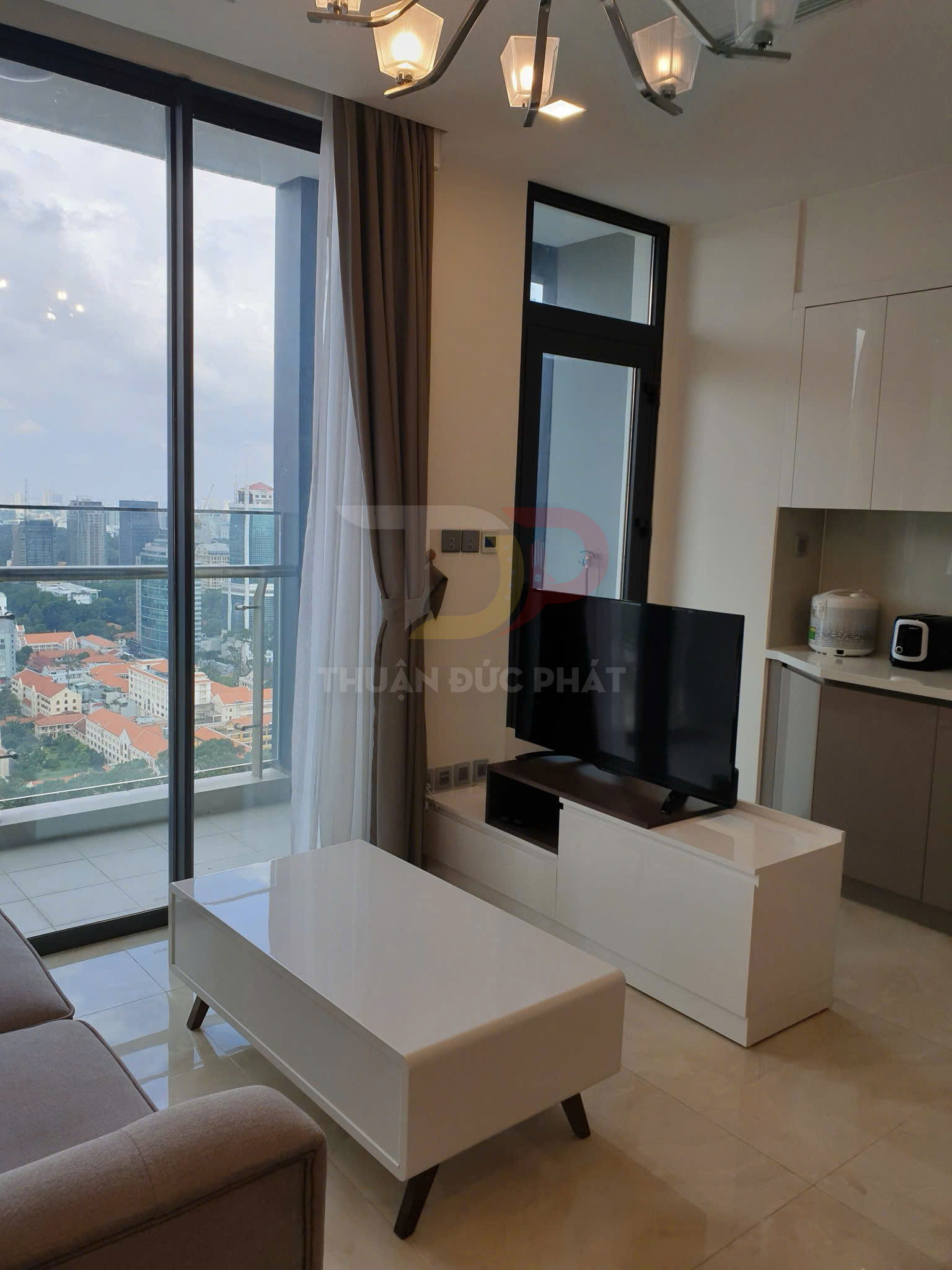 Bàn trà gỗ mặt trắng hiện đại trong phòng khách chung cư có sofa và kệ tivi cạnh cửa kính lớn
