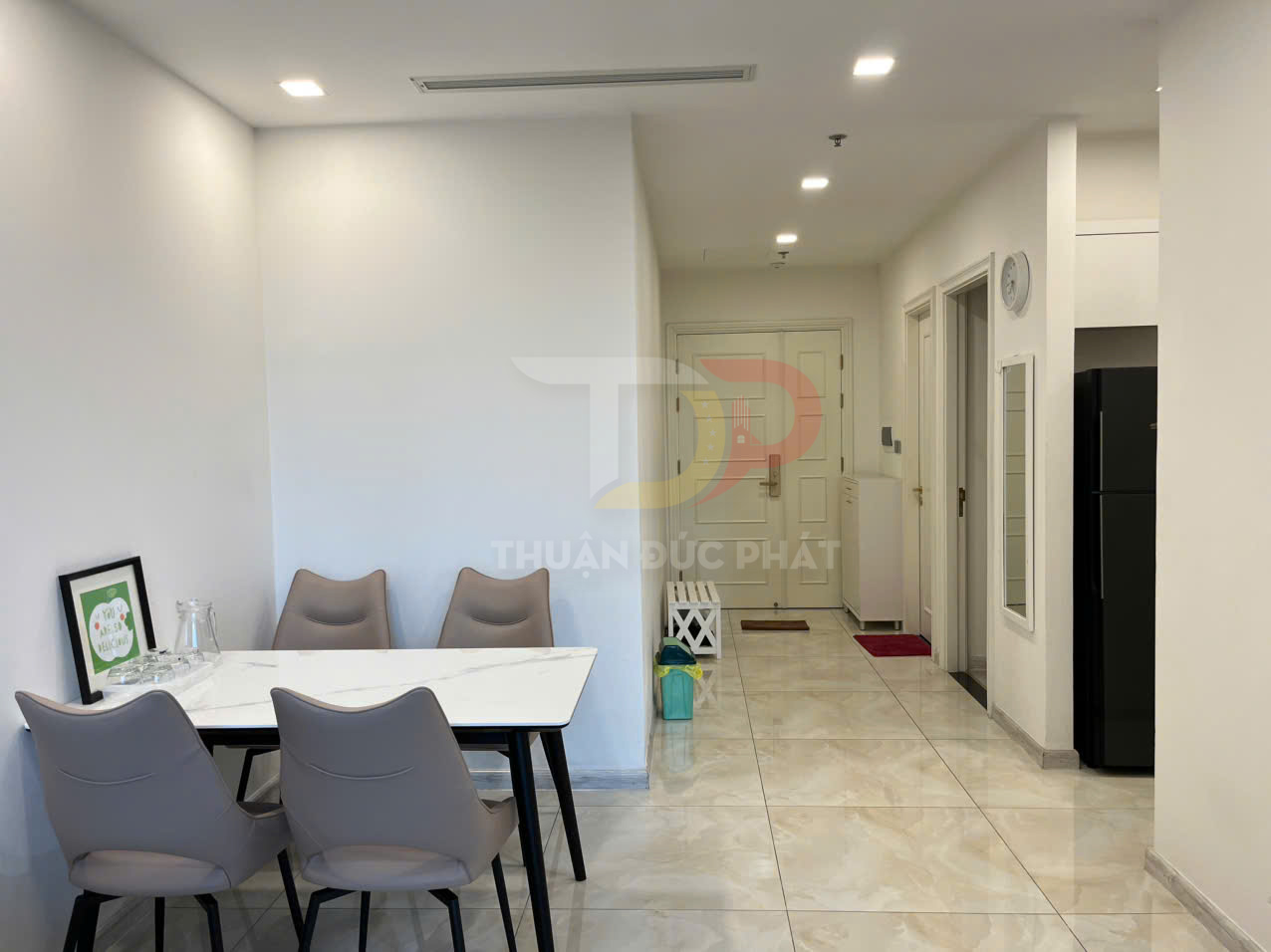 Bàn ăn mặt đá với bốn ghế da màu xám trong căn hộ hiện đại tông trắng sáng