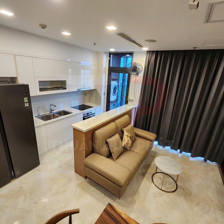 Căn hộ studio hiện đại với bếp trắng, sofa da màu nâu và bàn trà nhỏ cạnh rèm cửa tối màu