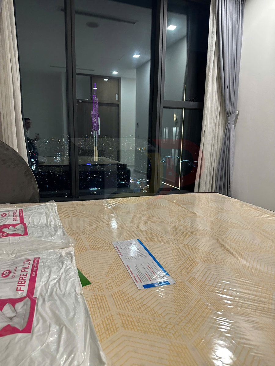 Nệm mới bọc nilon kèm gối fibre pillow đặt trong phòng ngủ chung cư view thành phố ban đêm