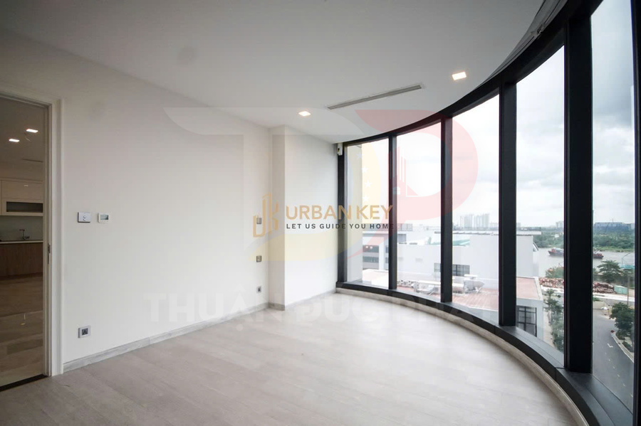 Căn hộ trống với cửa kính cong toàn cảnh, sàn gỗ sáng màu và bếp nối liền bên cạnh