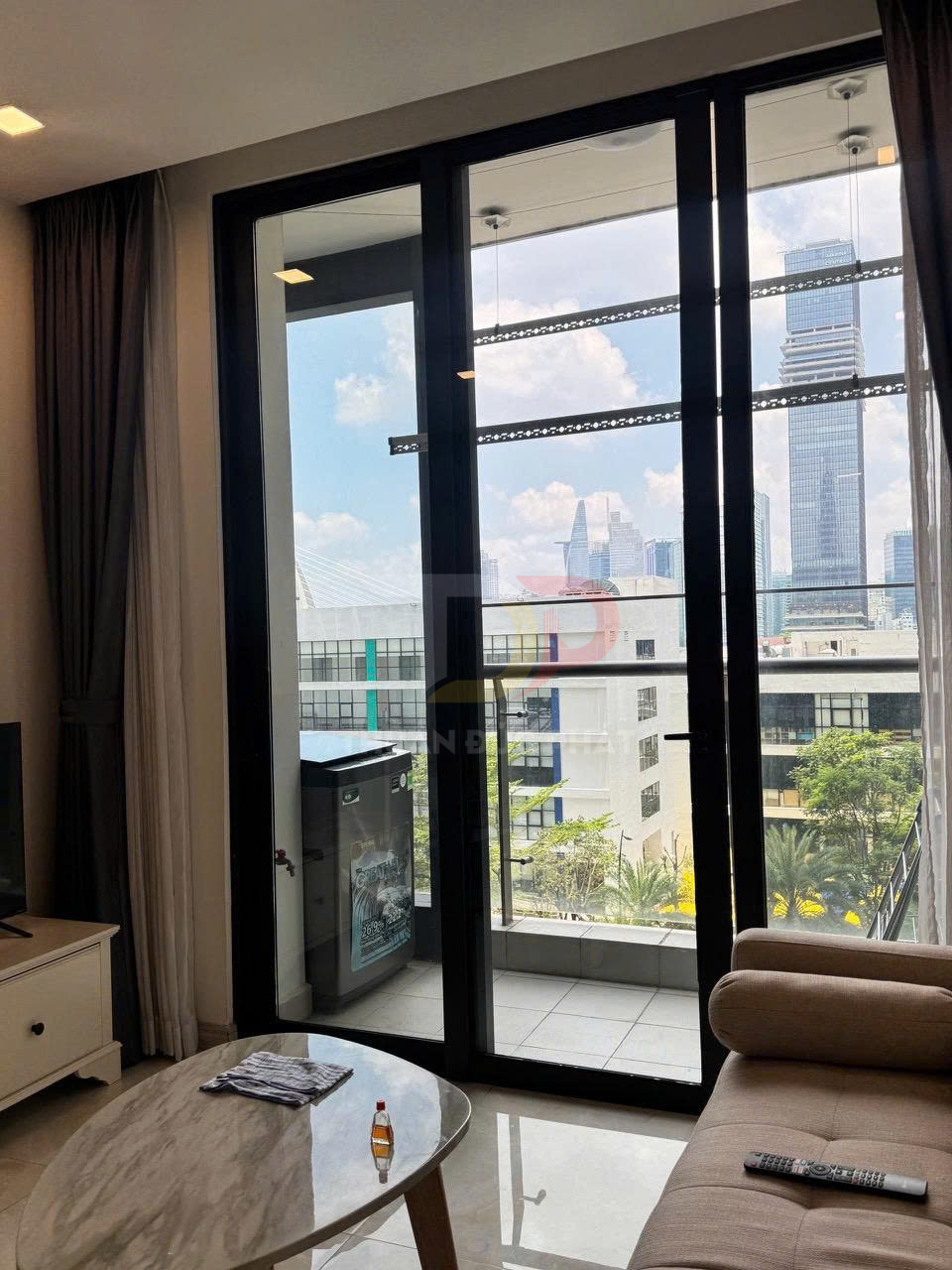 Phòng khách căn hộ với cửa kính lớn mở ra ban công, bàn trà và sofa nhìn ra view thành phố hiện đại