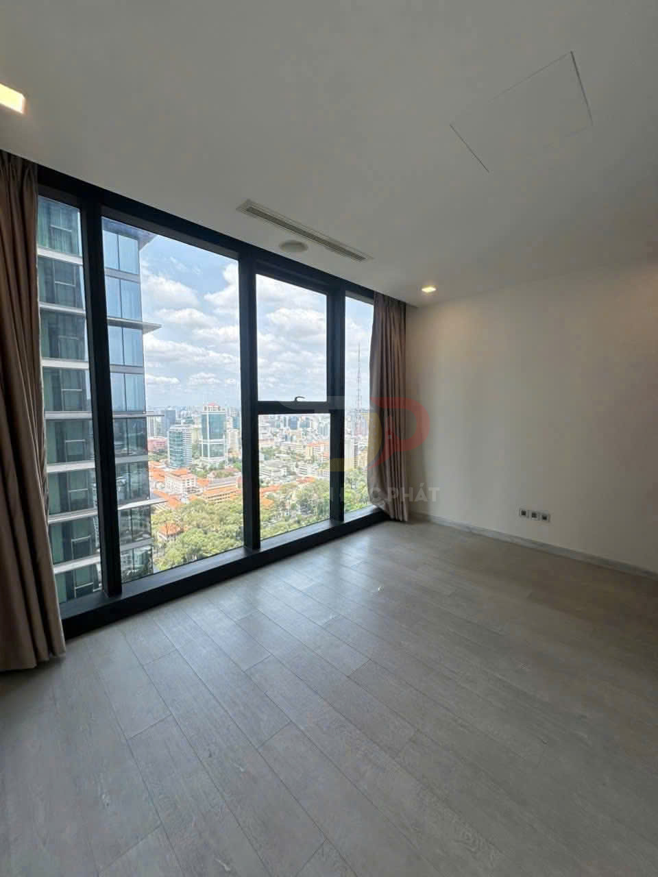 Căn hộ trống với cửa kính lớn sát sàn, rèm hai bên và view thành phố nhiều tòa nhà cao tầng