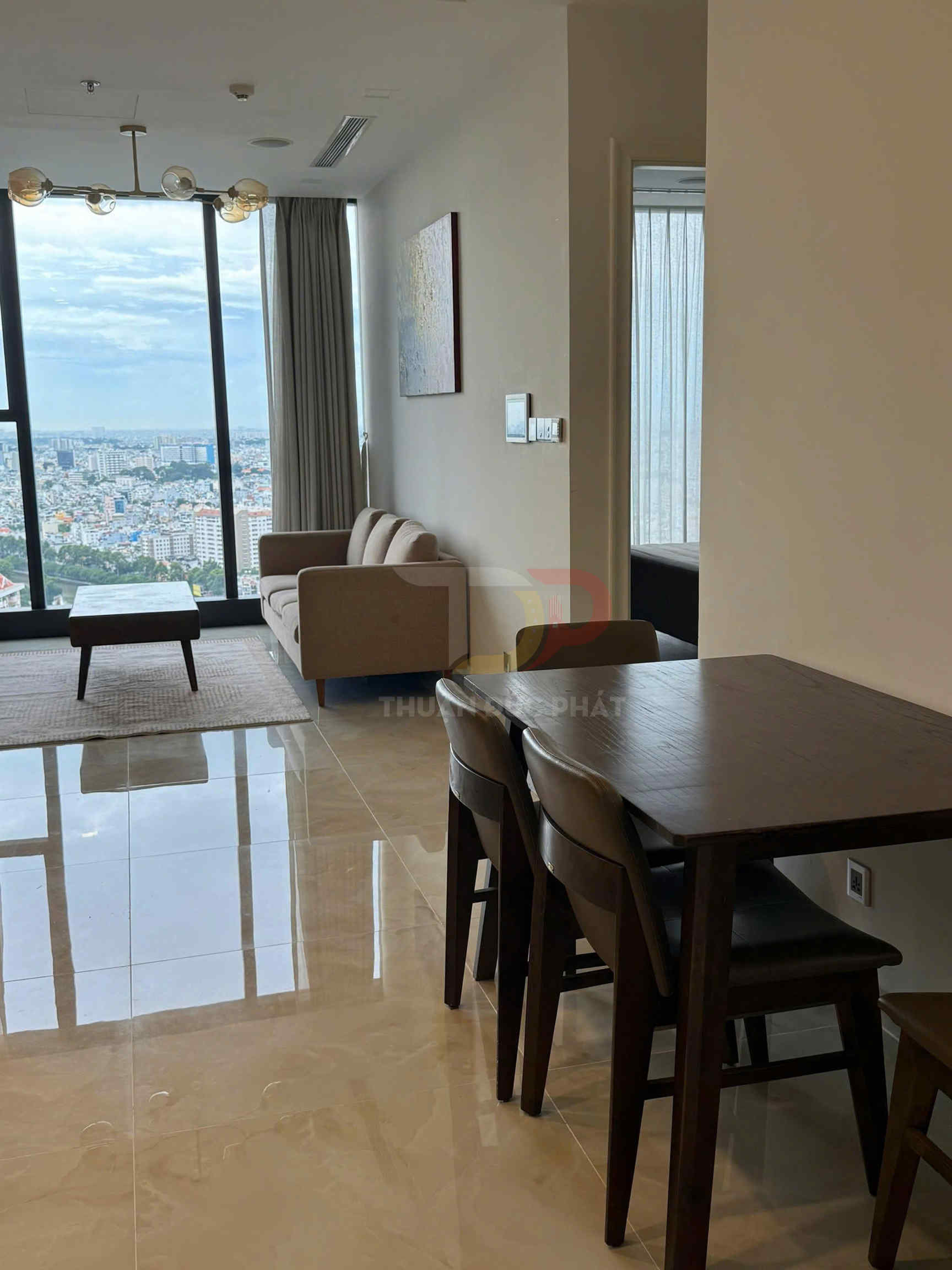 Bộ bàn ghế gỗ phòng ăn cạnh phòng khách chung cư có sofa và cửa kính lớn nhìn ra thành phố