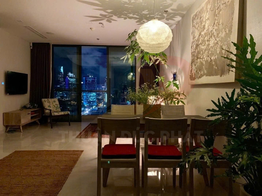 Phòng khách căn hộ cao cấp với bàn ăn gỗ, đèn trang trí và cửa kính lớn nhìn ra thành phố ban đêm