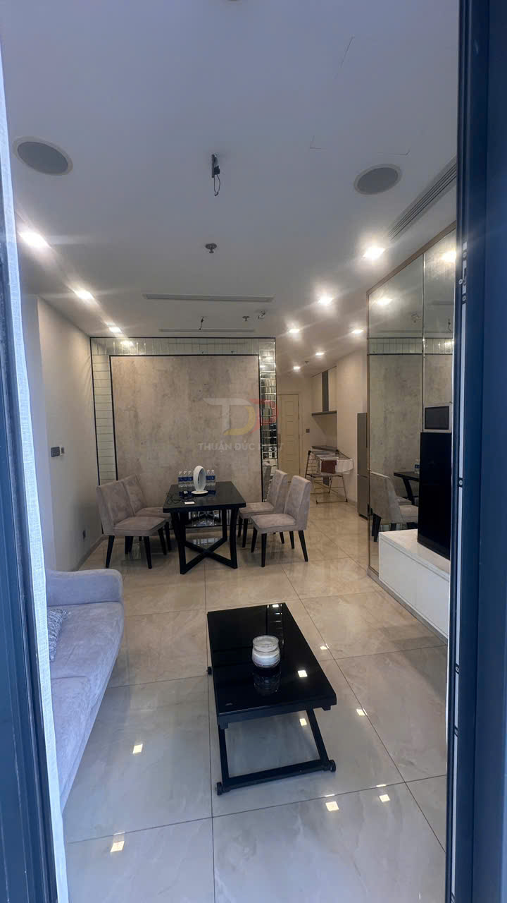 Phòng khách căn hộ hiện đại với sofa xám, bàn trà kính đen và bộ bàn ăn 4 ghế bọc nỉ