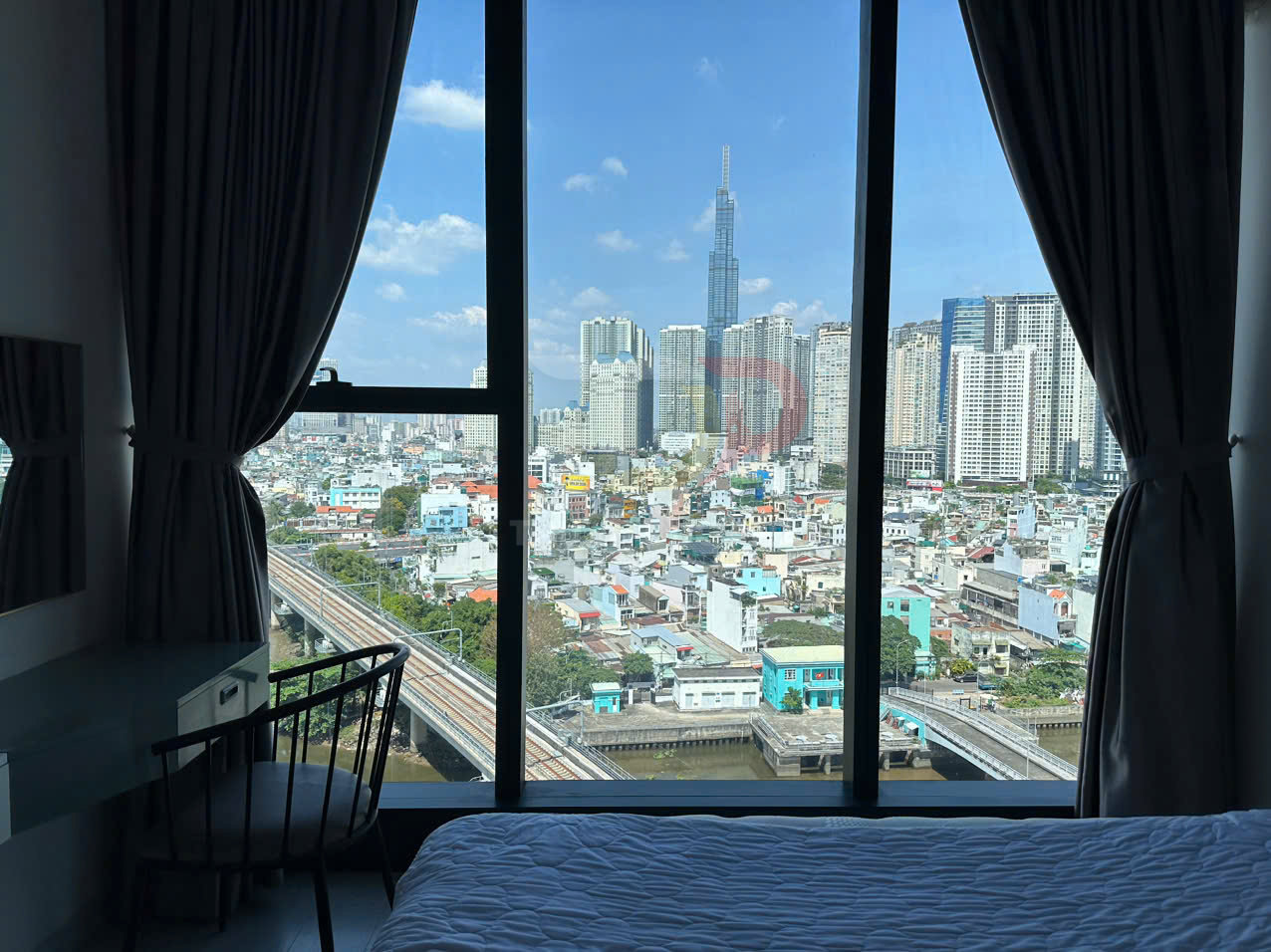 Phòng ngủ căn hộ với cửa sổ lớn nhìn ra Landmark 81 và khu đô thị hiện đại ban ngày