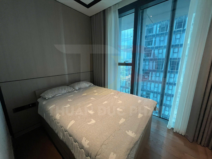 Giường ngủ đôi với chăn ga màu xám họa tiết đơn giản cạnh cửa sổ kính lớn view thành phố