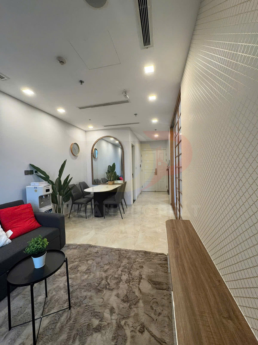 Phòng khách chung cư hiện đại với sofa xám, bàn trà tròn đen, thảm lông và bàn ăn cạnh gương lớn