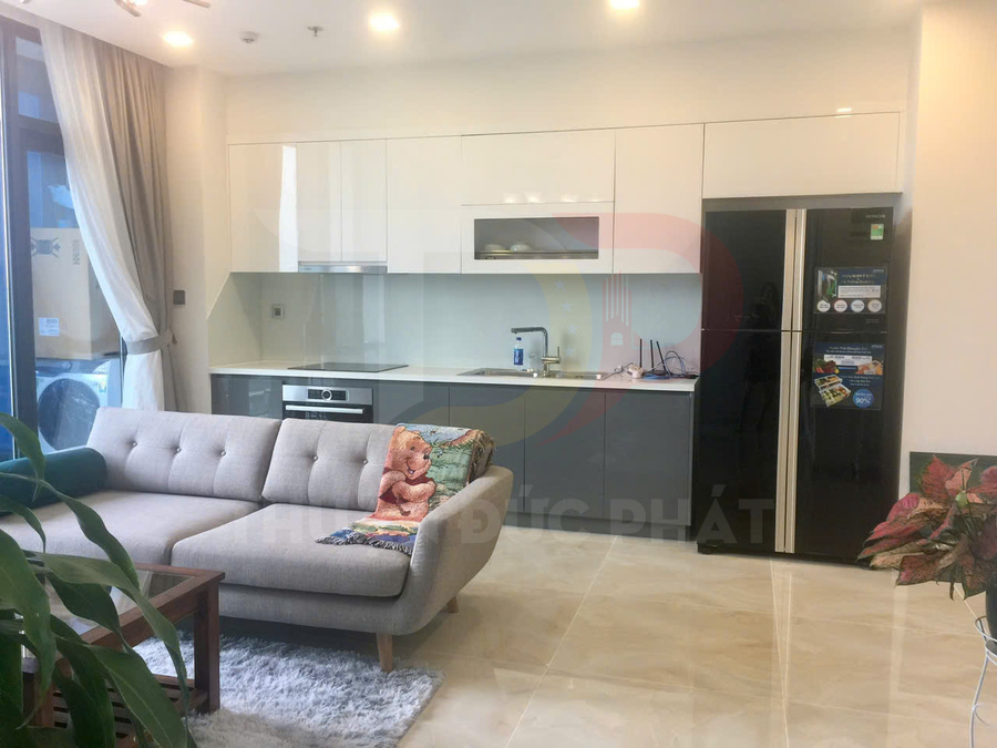 Phòng bếp hiện đại với tủ bếp trắng xám, sofa chữ L và tủ lạnh hai cánh màu đen