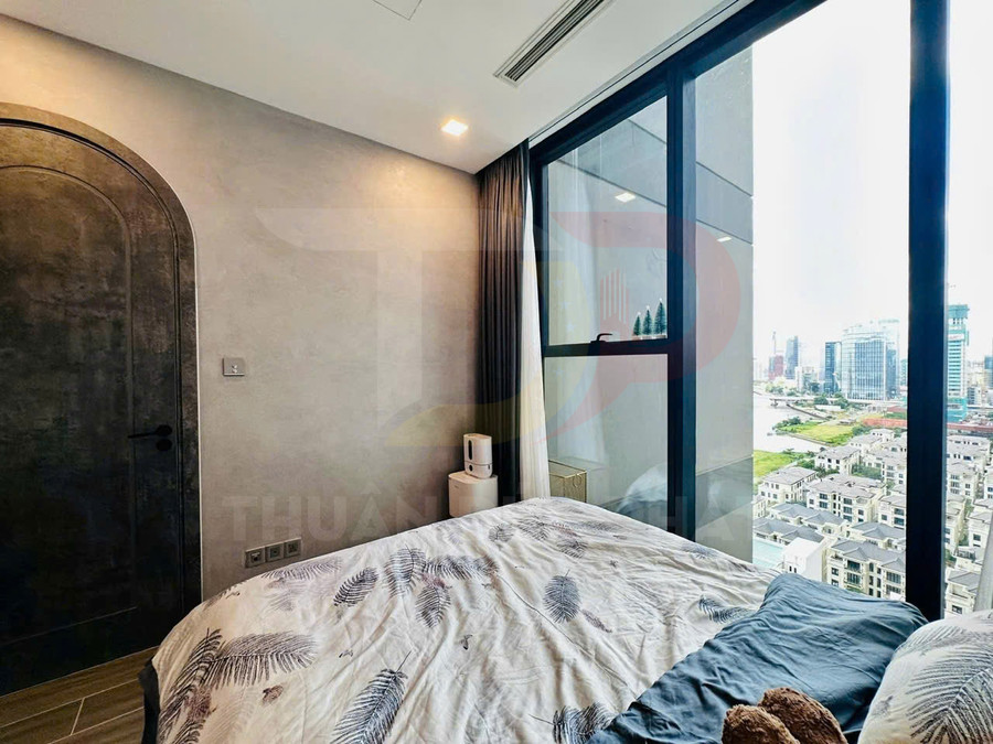 Phòng ngủ chung cư hiện đại với giường cạnh cửa kính lớn nhìn ra thành phố và khu dân cư cao cấp